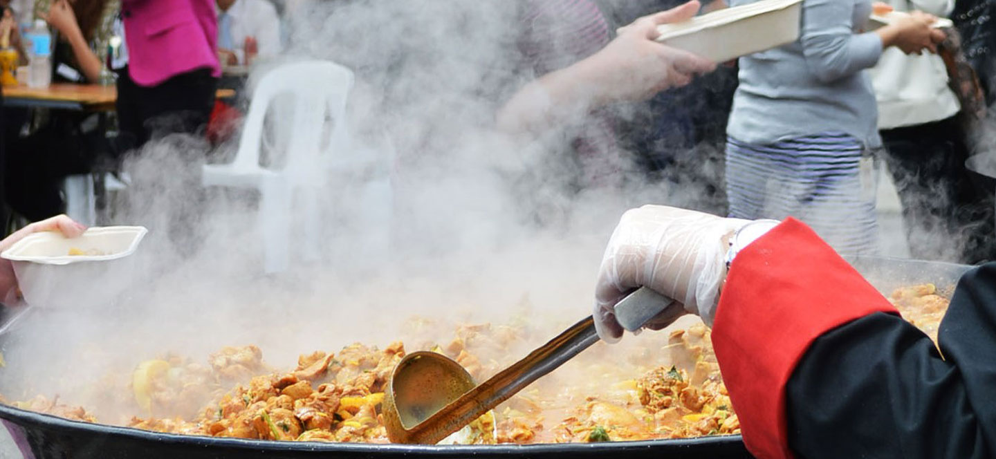 Chef with ladle over a wok with steamming food