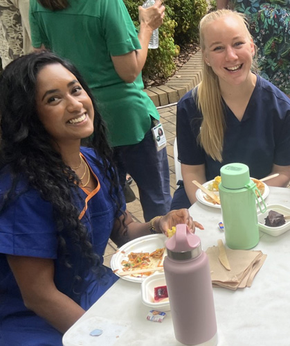 Two colleagues smiling at a table with plates of food