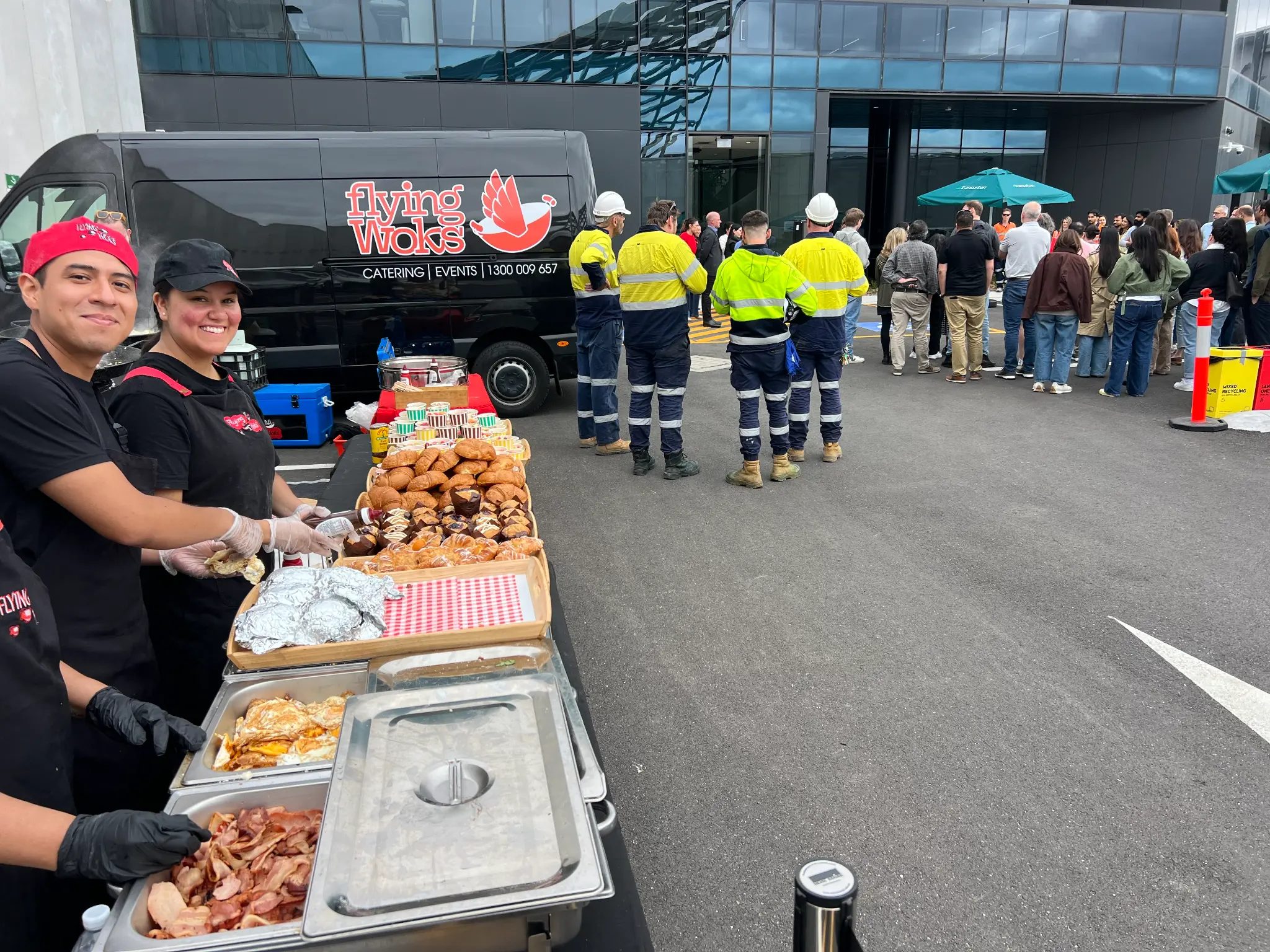 Flying Woks breakfast catering Melbourne - staff serving crowd with bacon eggs and pastries