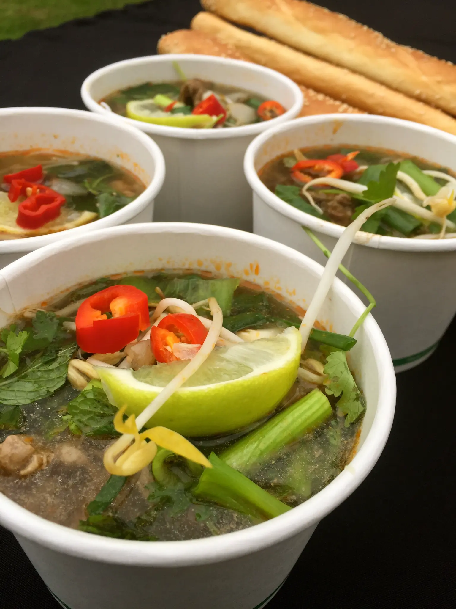 Pho bo soup cups with fresh herbs and bread