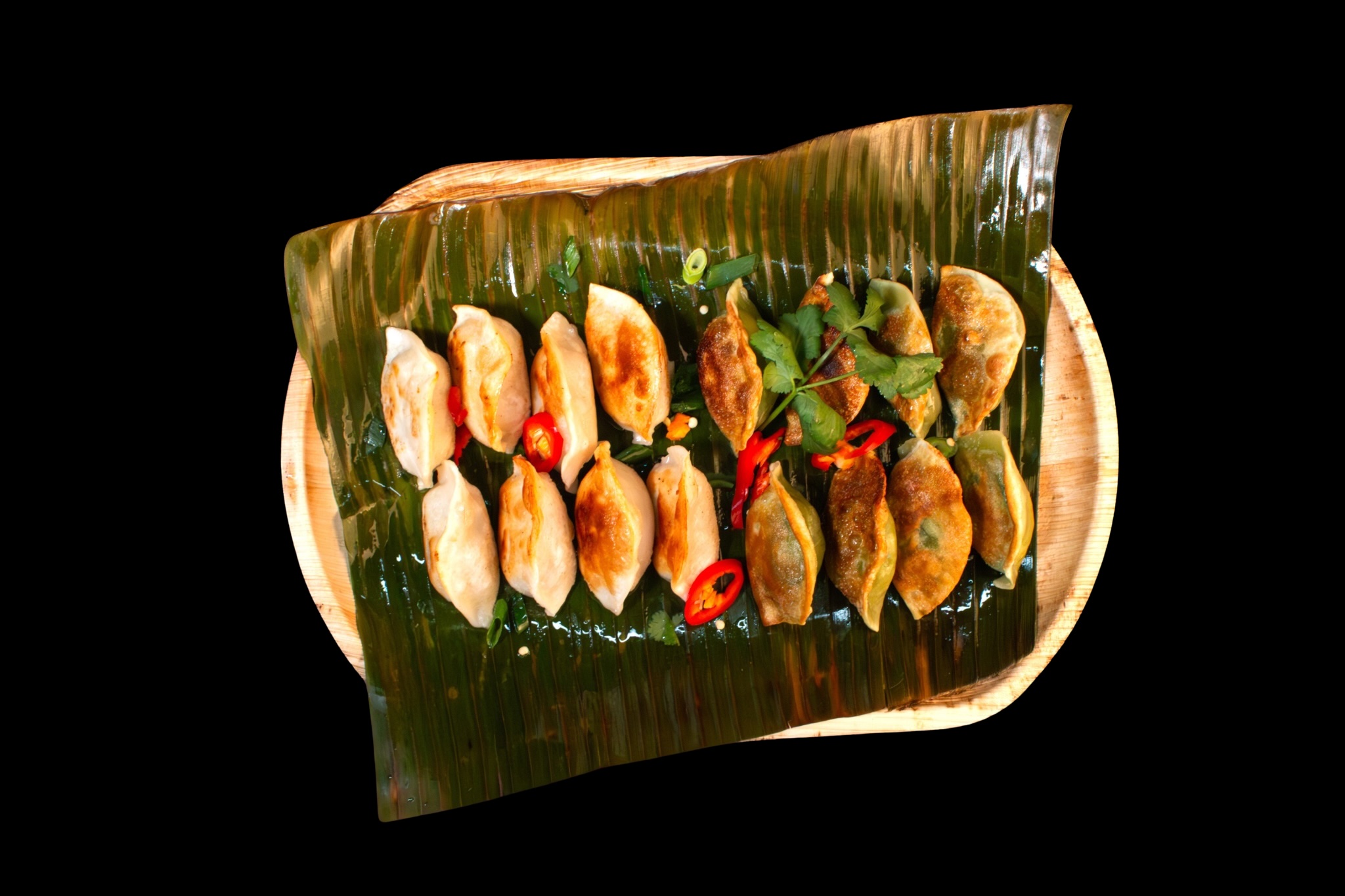 Flying Woks pan-fried dumplings on banana leaf palm tray — premium finger food catering presentation