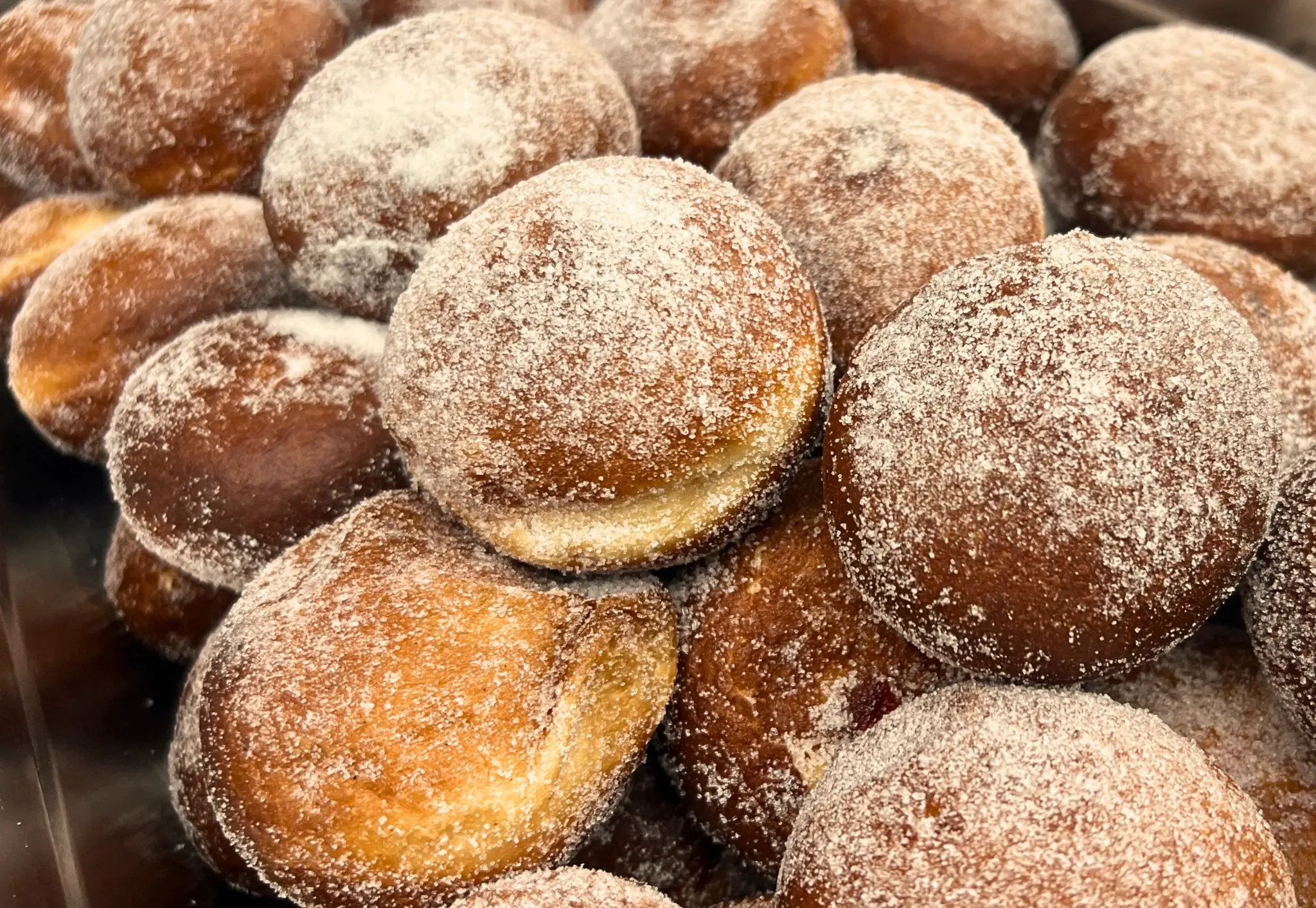 Close-up of fresh sugar-dusted jam doughnuts cooked live on site