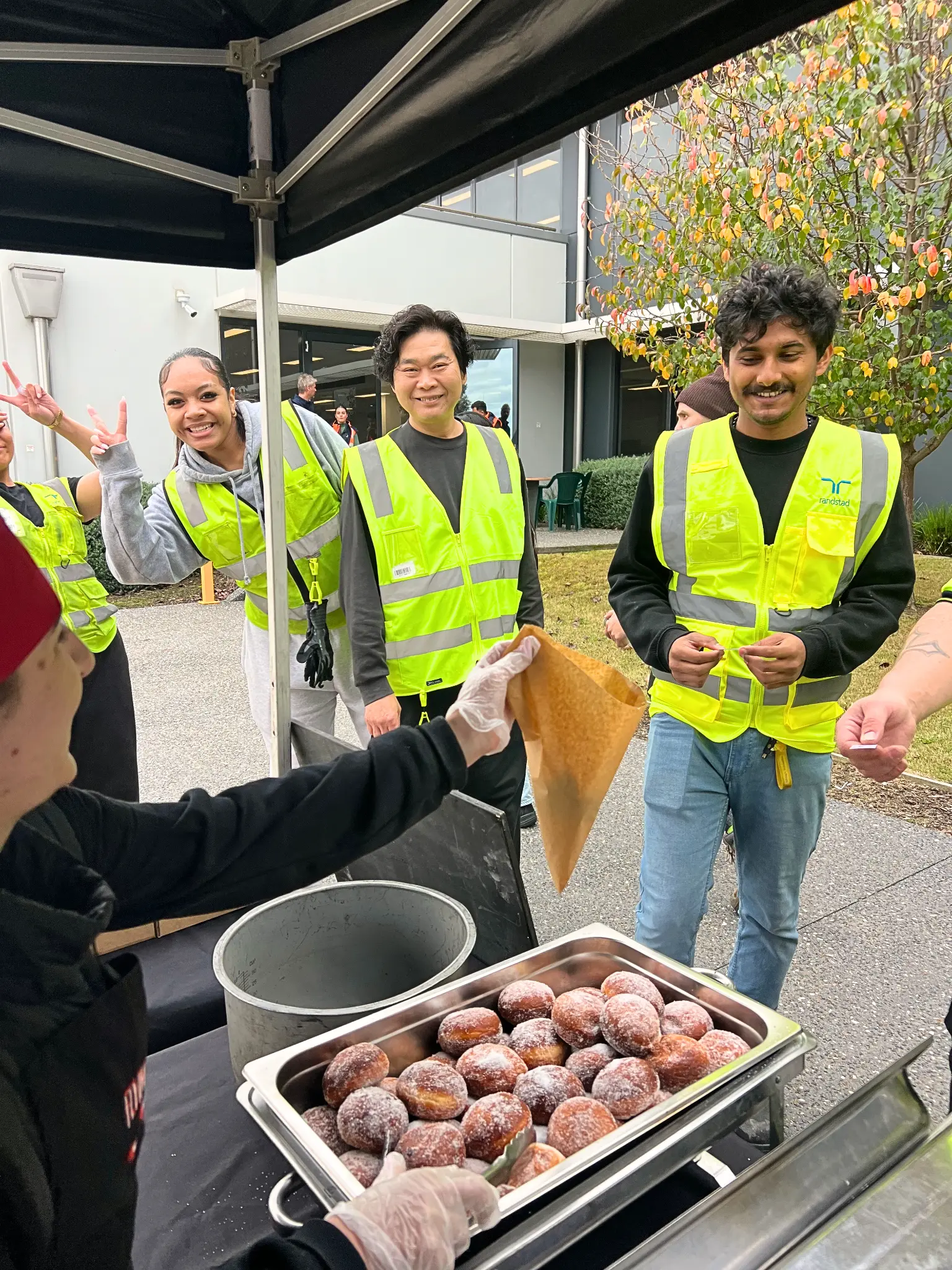 Flying Woks staff handing out fresh hot jam doughnuts to workers at a corporate event