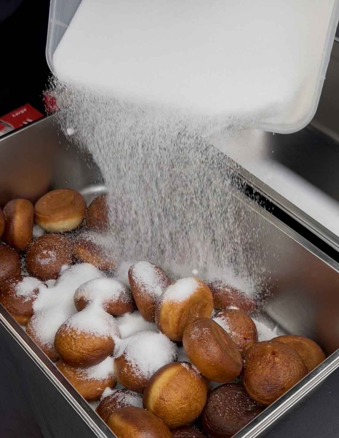 Sugar being poured over fresh hot jam doughnuts at a Flying Woks corporate event